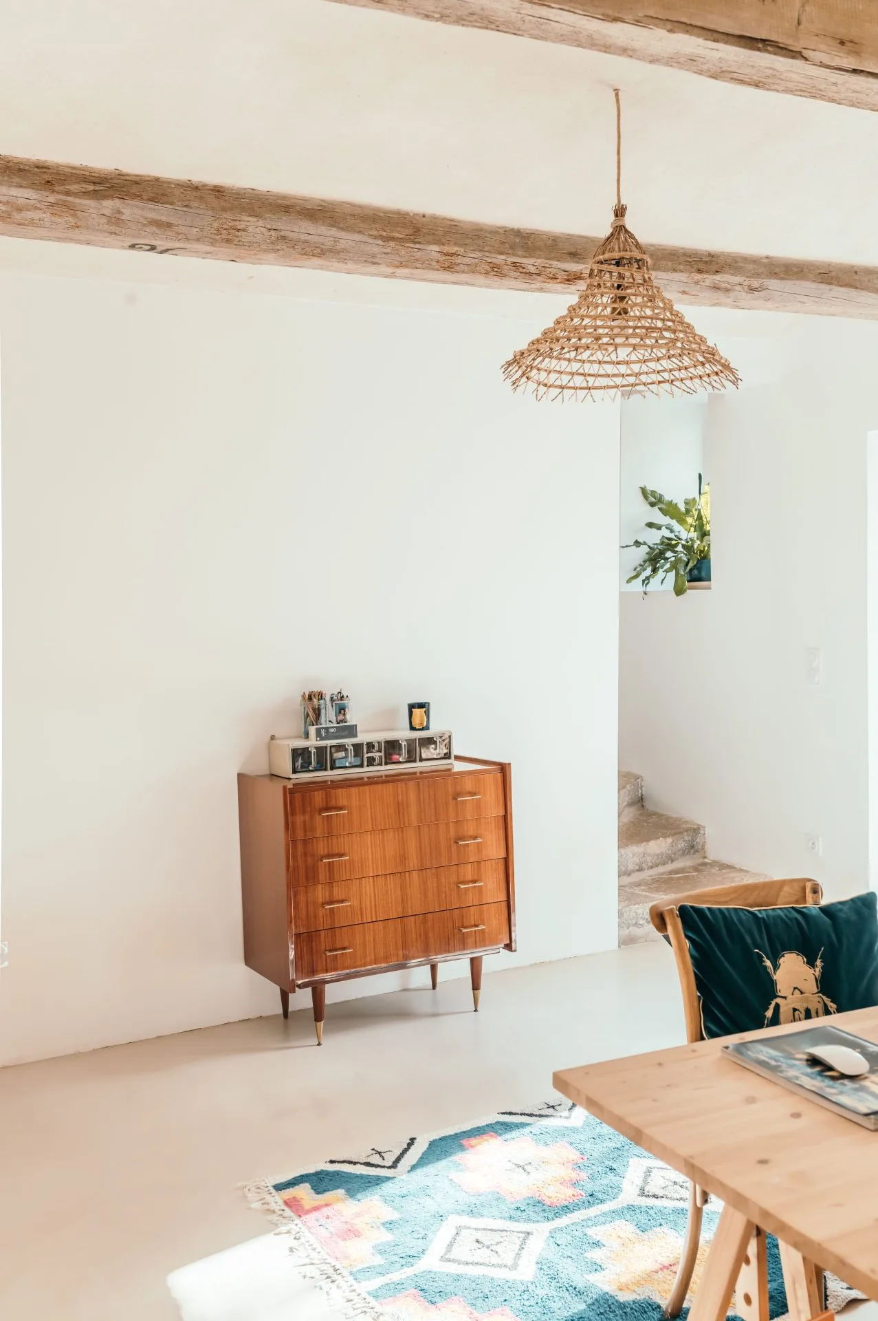 commode-bureau Espace bureau décoré avec un tapis coloré, un luminaire en matière naturelle et une commode vintage en bois vernis.